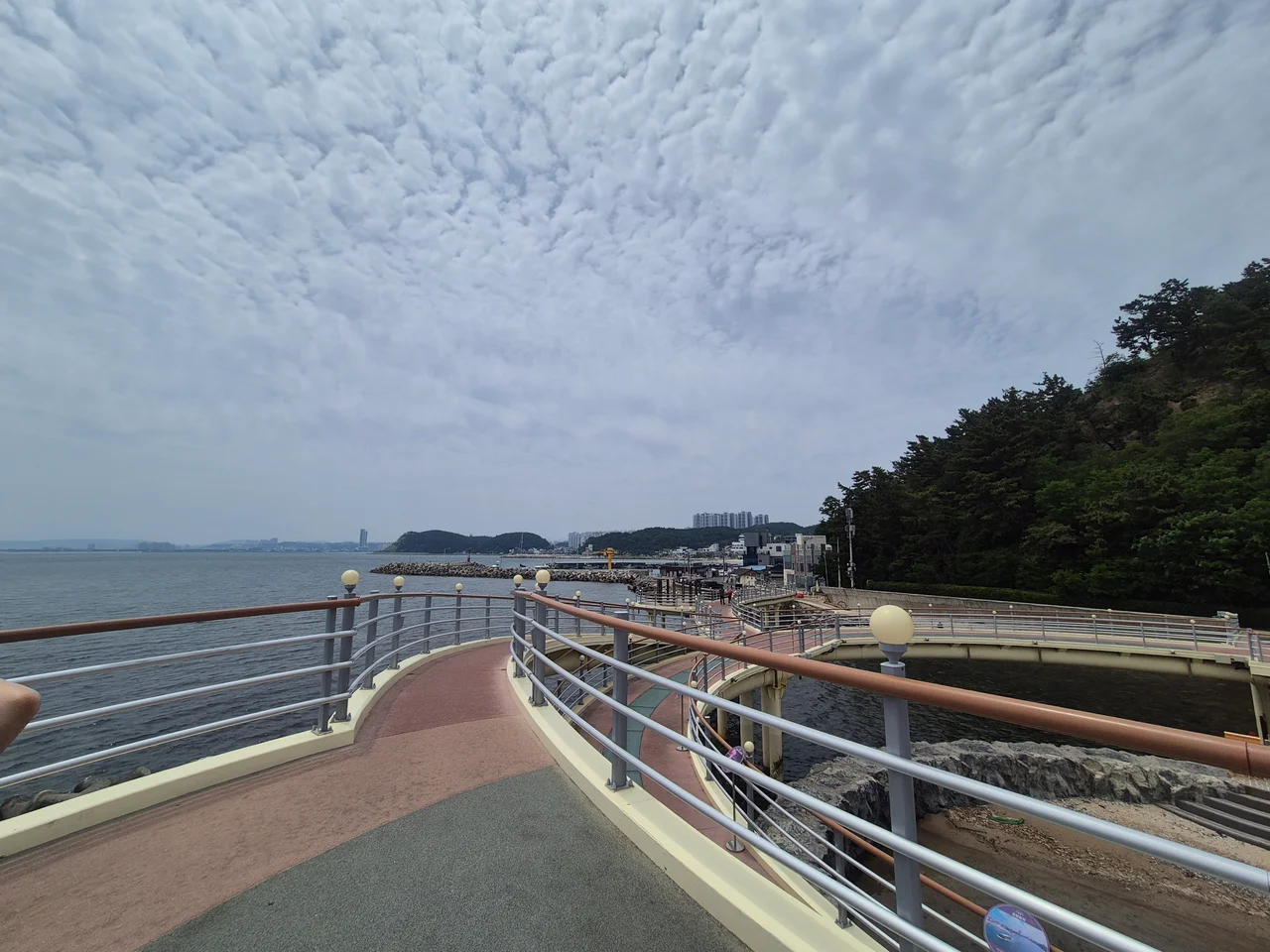 나선형으로 굽이치며 회전하는 스카이워크 보행로와 먼바다 전경