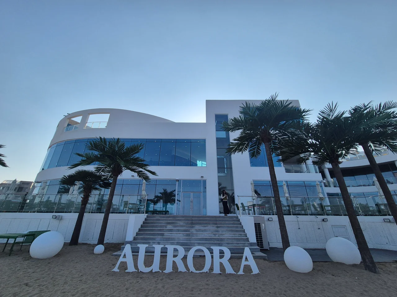야자수와 AURORA 조형물이 어우러진 모던한 포항 대형 카페 외관