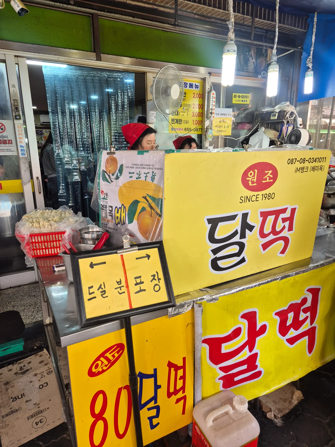 노란색 달떡 간판 아래 드실 분과 포장 줄 안내판이 세워진 정겨운 시장 떡볶이집 전경