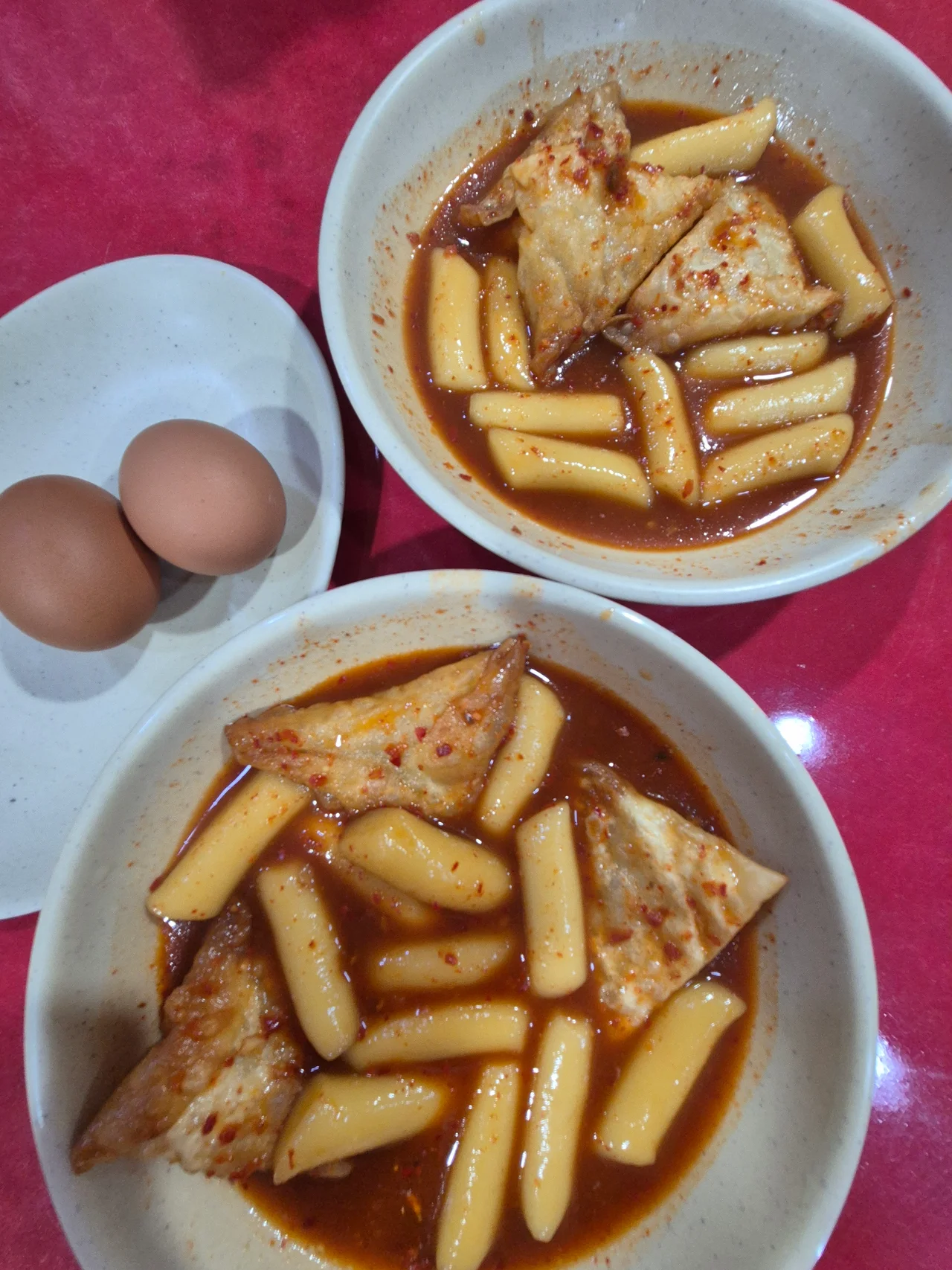빨간 테이블 위에 놓인 푸짐한 달떡 두 그릇과 찐계란 두 알의 먹음직스러운 비주얼