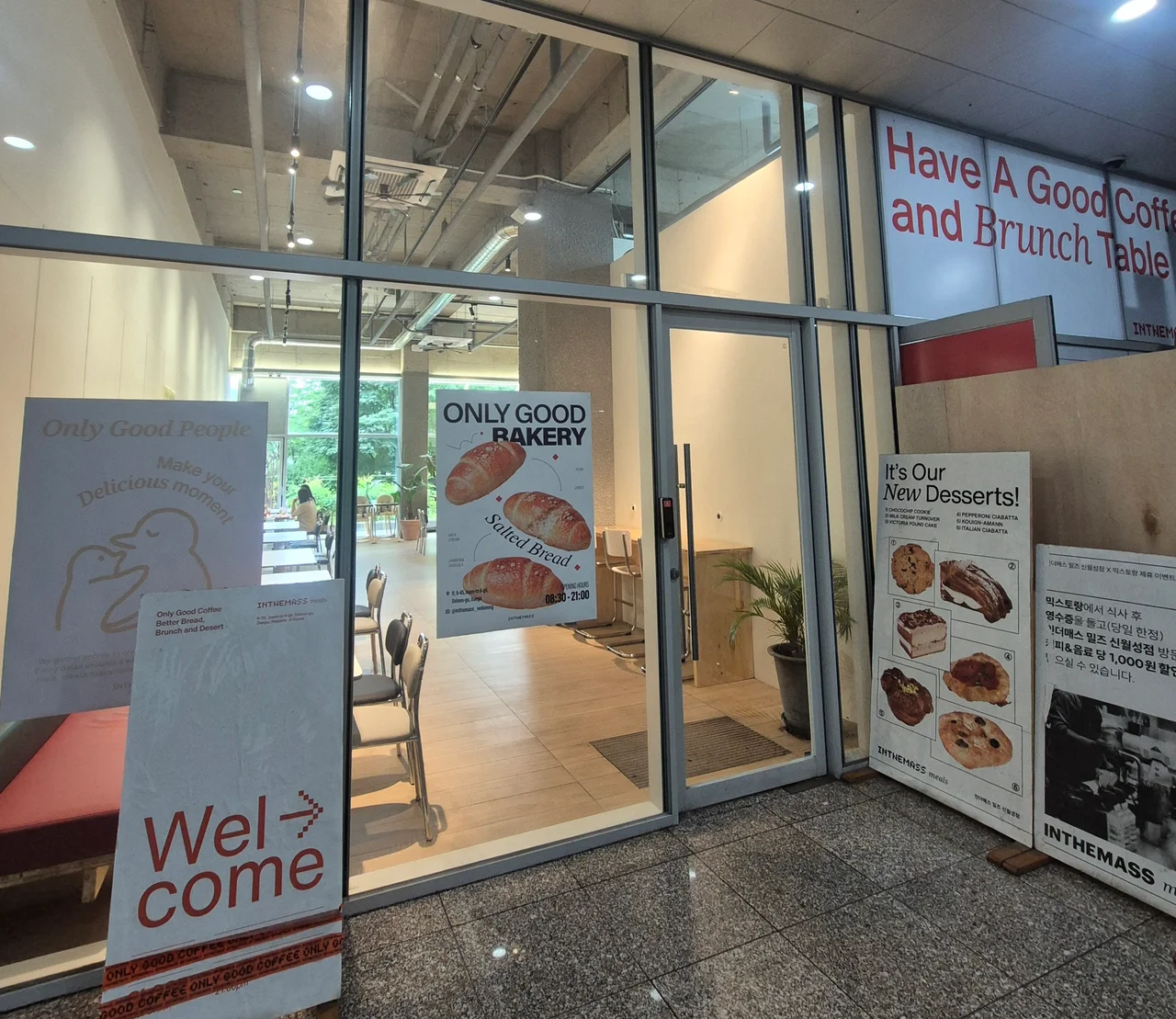 Only Good Bakery 포스터와 웰컴 입간판이 서 있는 카페 출입구 전경
