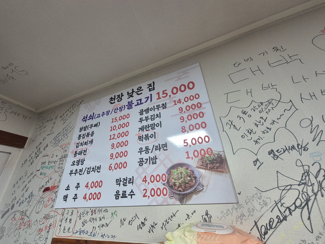 다양한 한식 안주와 주류 가격이 적혀 있는 천장낮은집 벽면 메뉴판
