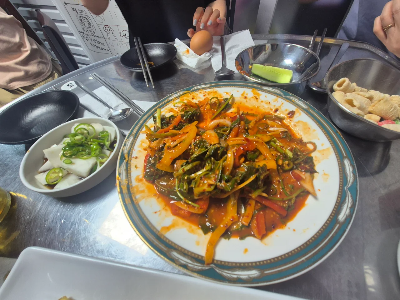 스틸 테이블 위에 정갈하게 차려진 기본 겉절이 샐러드와 시원한 무 절임 반찬