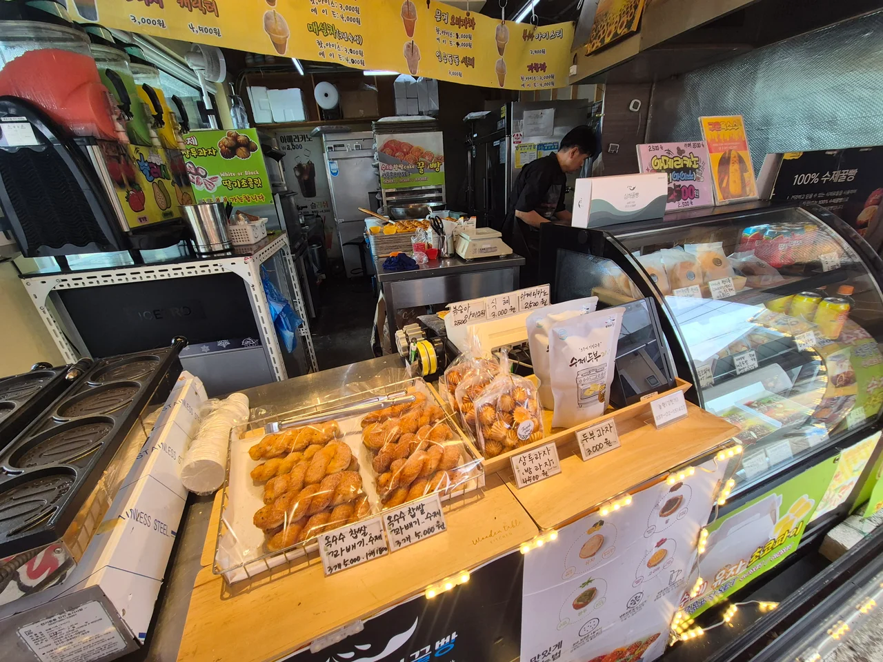 깨끗한 주방 내부와 갓 구워낸 꽈배기, 상투과자가 푸짐하게 진열된 카운터 모습