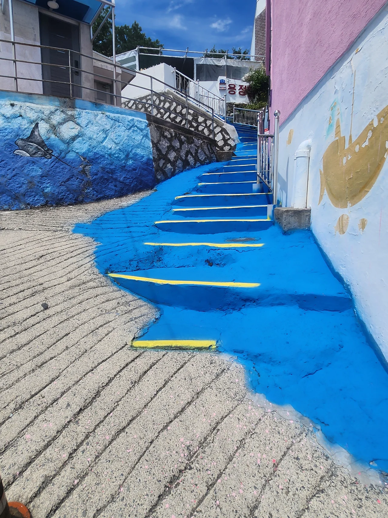 파란색으로 강렬하게 채색되고 노란 경계선이 그려진 계단길