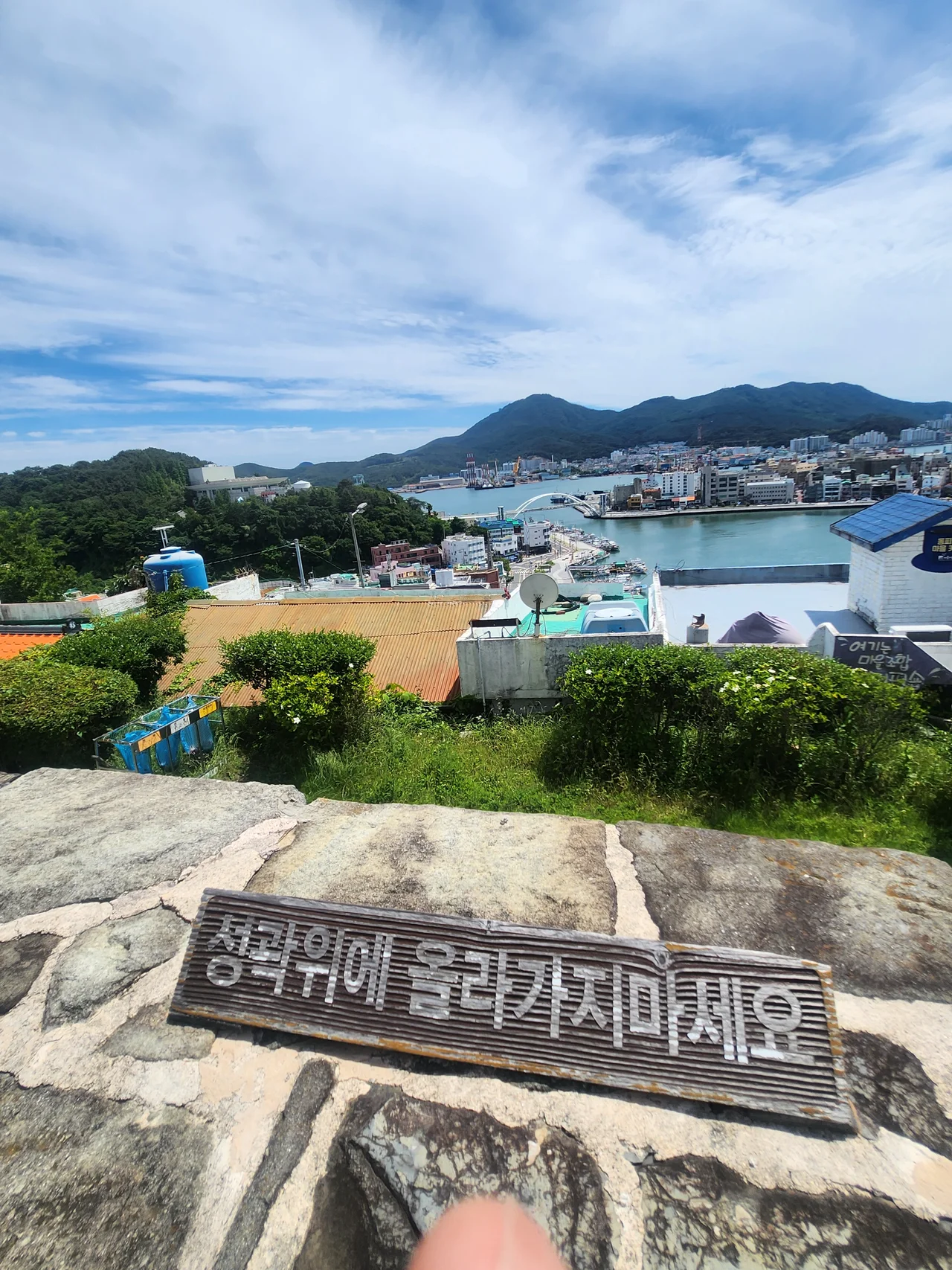 성곽 위에 올라가지 마세요라고 쓰인 안내 표지판 너머의 강구안 뷰