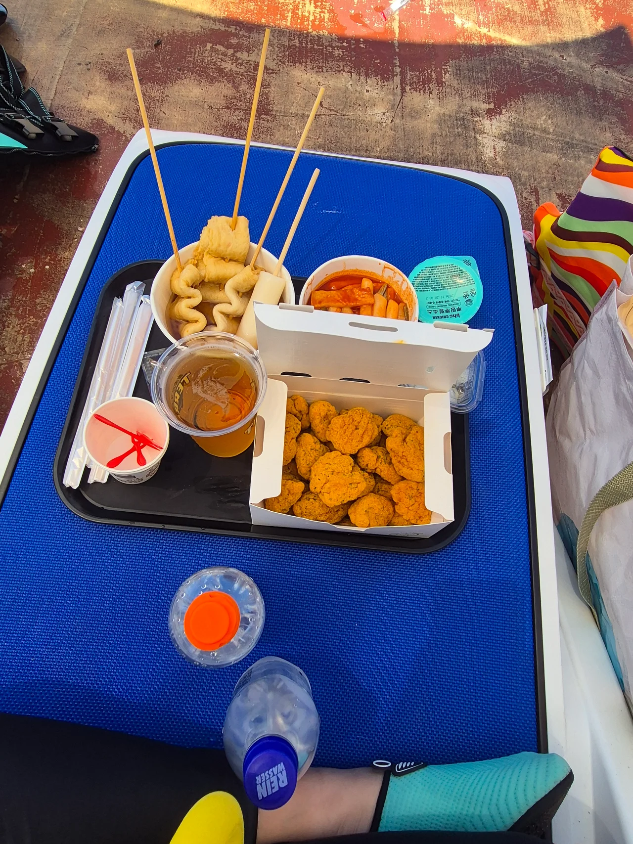 썬베드 위 트레이에 차려진 치킨과 떡볶이 어묵 맥주 간식