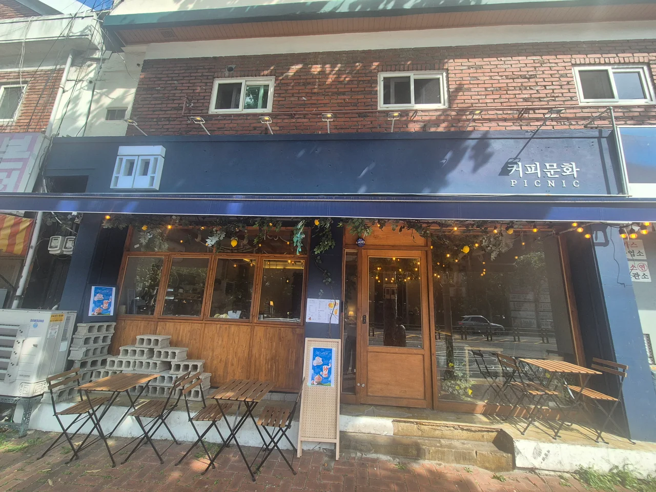 가게 앞 인도 위에 놓인 나무 야외 테이블과 의자들
