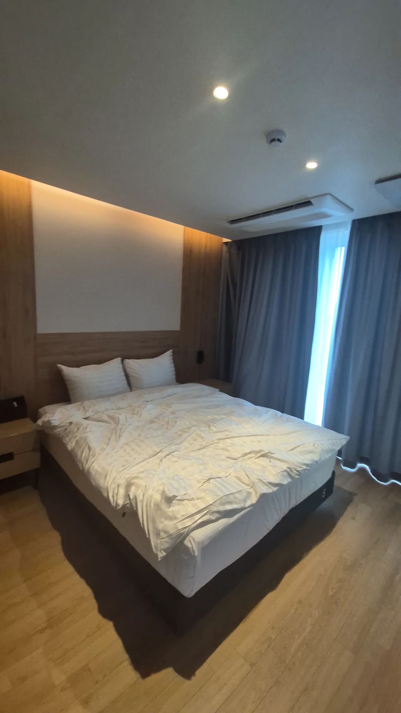 정갈한 화이트 침구와 간접 조명이 돋보이는 더블 베드 침실