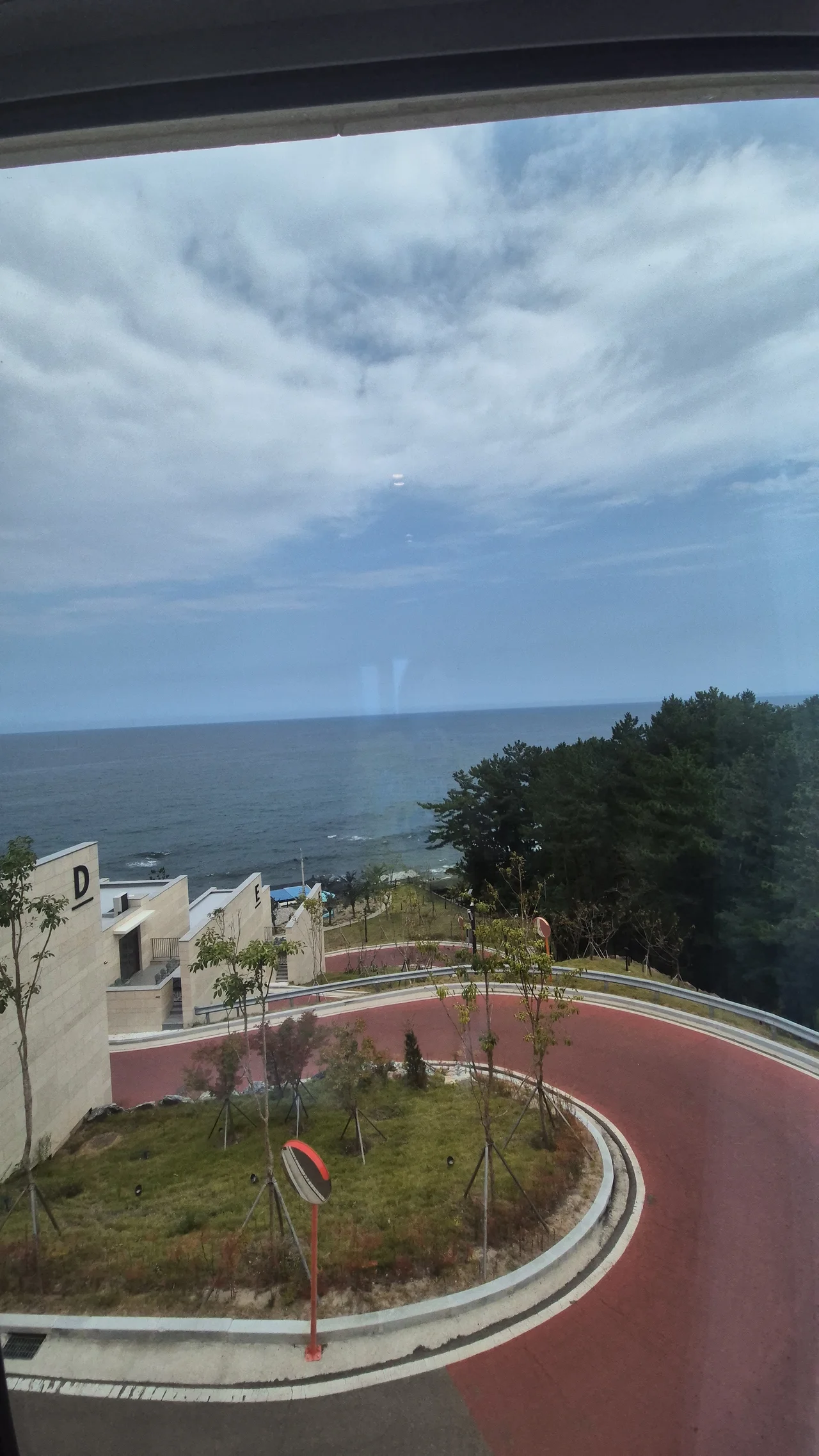 2층 창문 밖으로 내려다보이는 리조트 단지 내 도로와 수평선