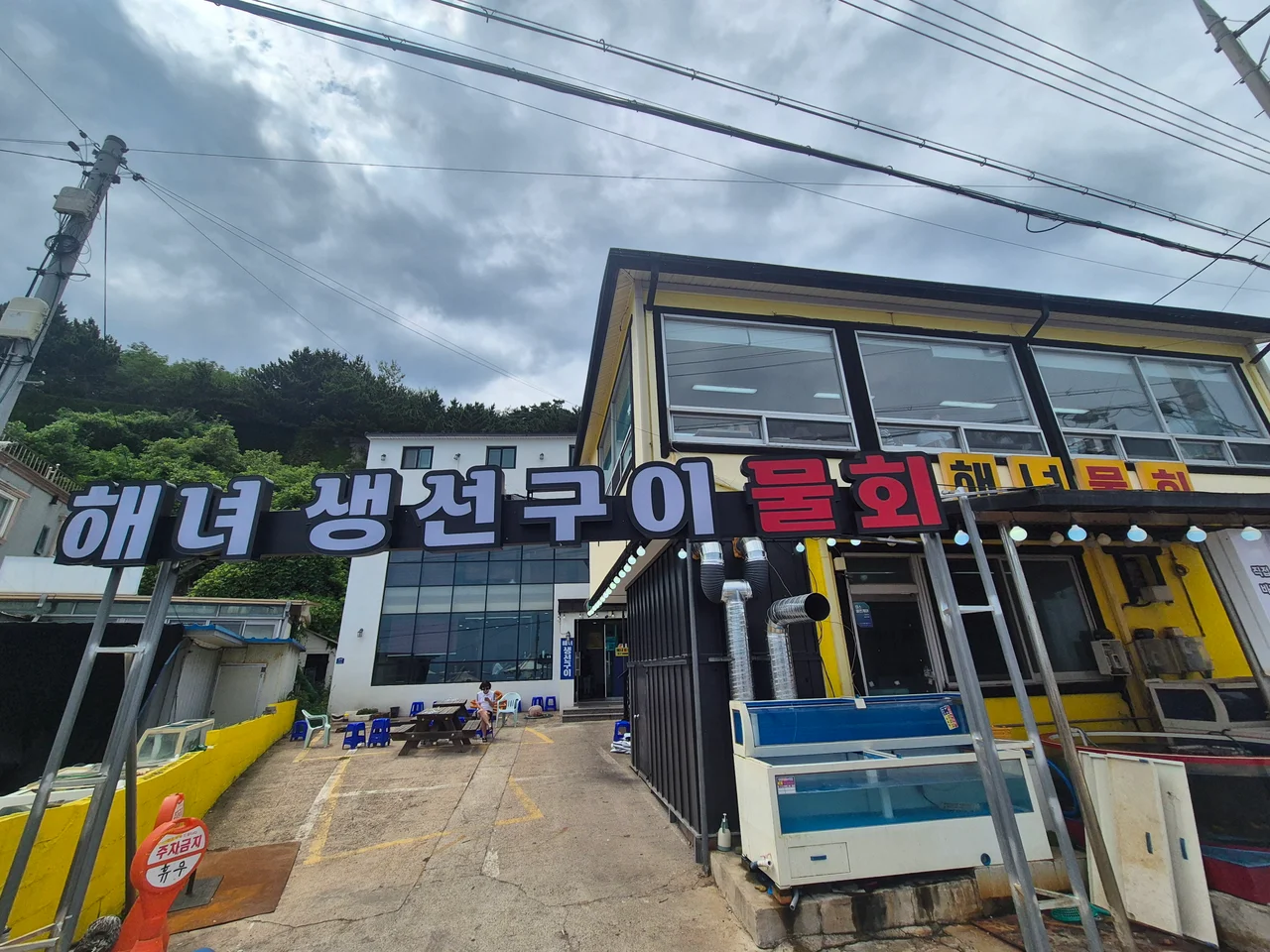 노란색 해녀물회 건물과 해녀 생선구이 간판이 보이는 식당 외관