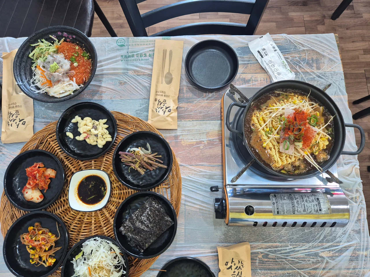 테이블 위에 차려진 기본 반찬과 물회, 매운탕 라면 냄비