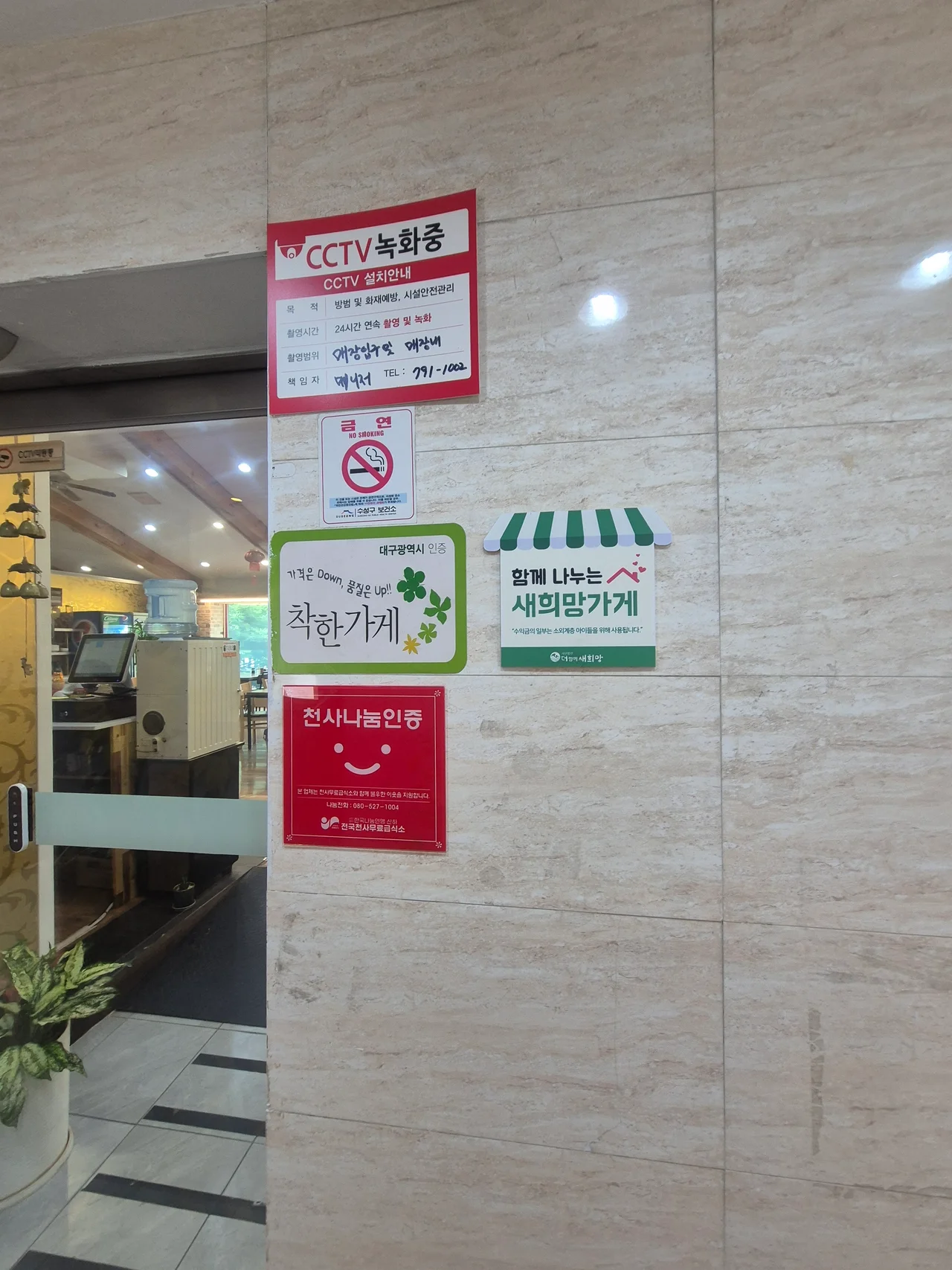 입구 벽면에 붙은 착한가게 및 천사나눔 인증 표지판