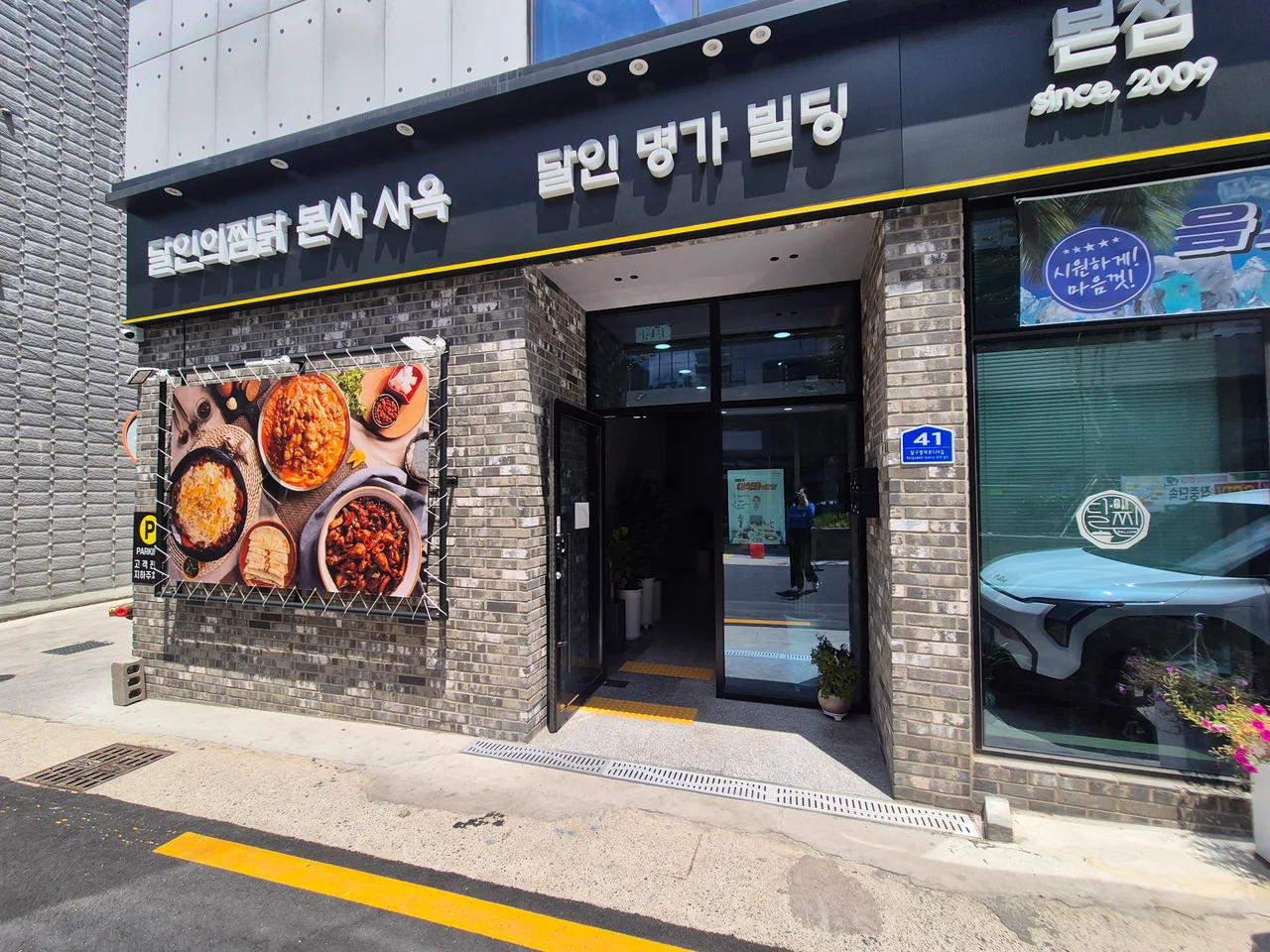 달인명가빌딩 입구와 벽면에 걸린 찜닭 메뉴 사진
