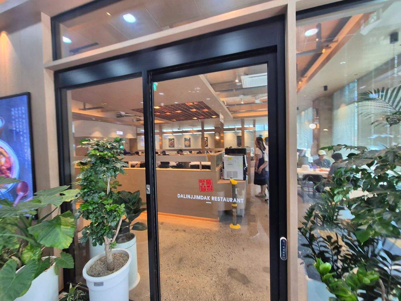 화분들이 놓인 달인의찜닭 유리 자동문 입구