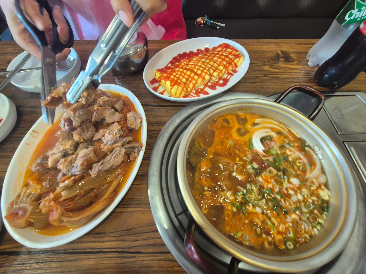 가위와 집게로 고기를 자르고 있는 손의 모습
