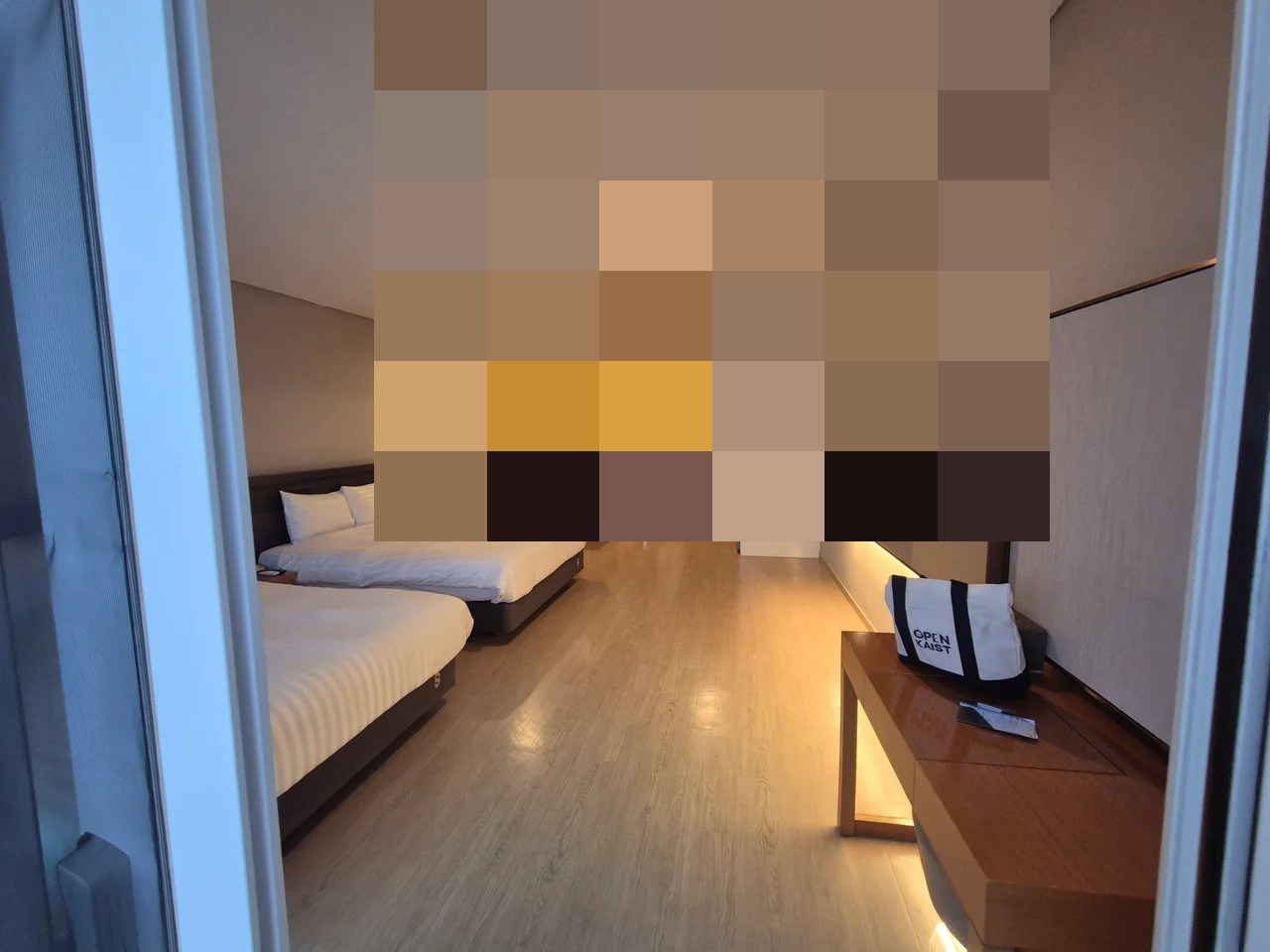 아늑한 간접 조명과 푹신한 화이트 침구가 구비된 넓은 패밀리형 객실 침실 내부