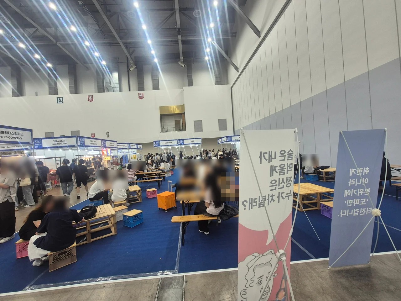 전시장 중앙에 마련된 파란색 카펫과 우드 테이블 휴식 공간